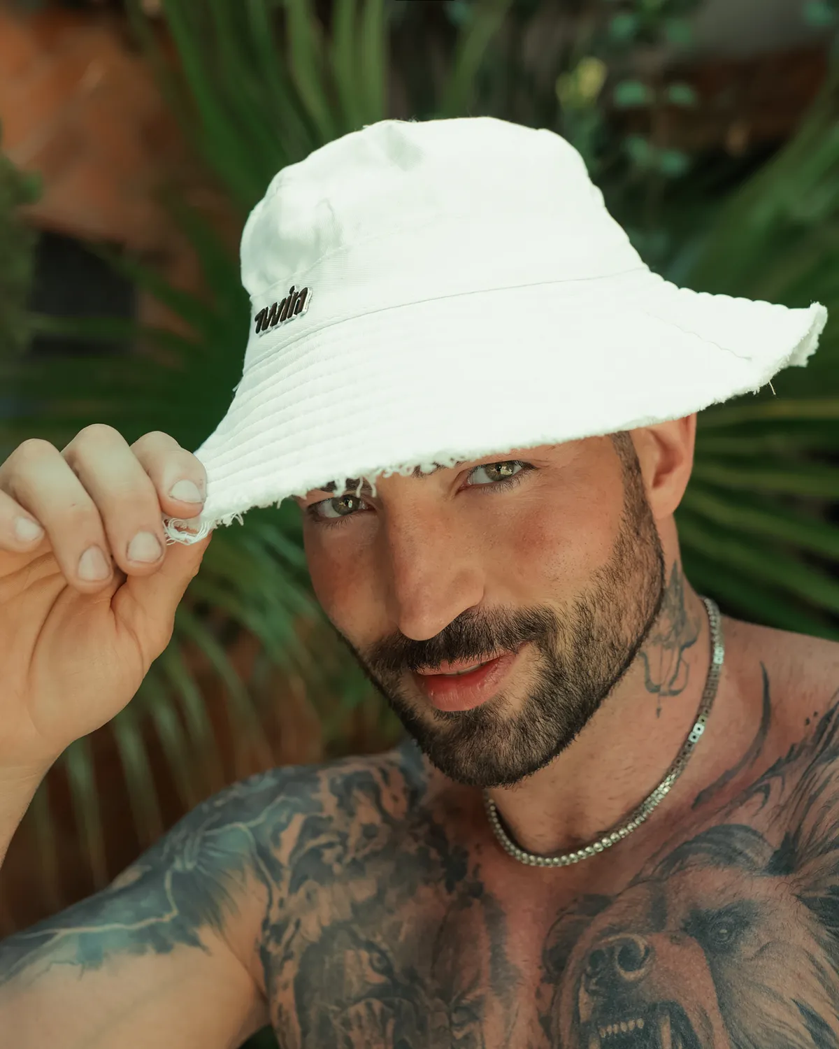 Maximo Garcia com um chapéu branco de pescador, sorrindo para a câmera